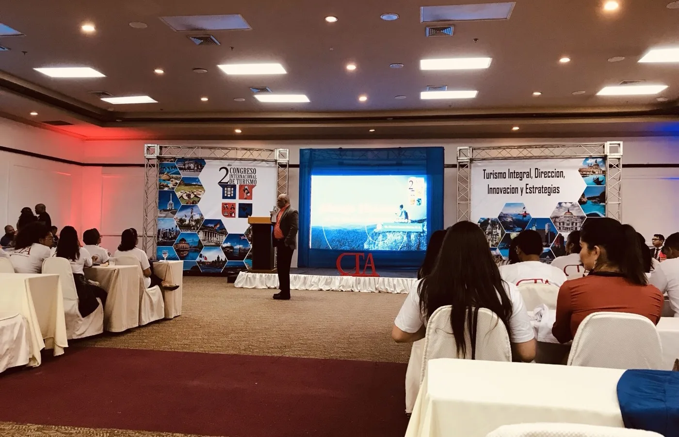 Plenaria del congreso internacional de turismo operado por AQT Ecuador: ponente en escena y sala con asistentes