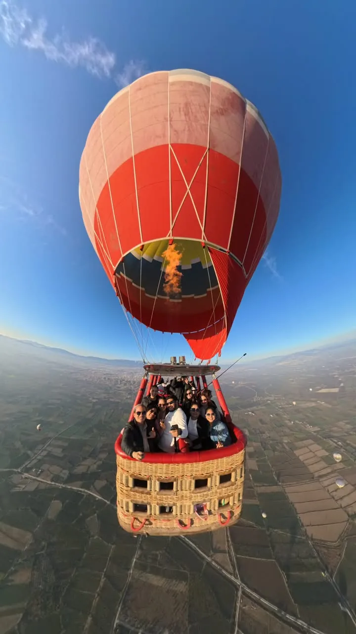 Viajeros ecuatorianos de AQT en la cesta de un globo aerostático sobre Capadocia, con el quemador encendido