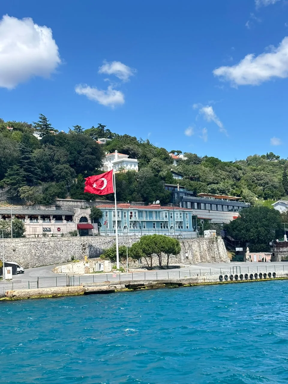 Orilla del Bósforo en Estambul con una bandera turca ondeando frente a casas de madera junto al agua