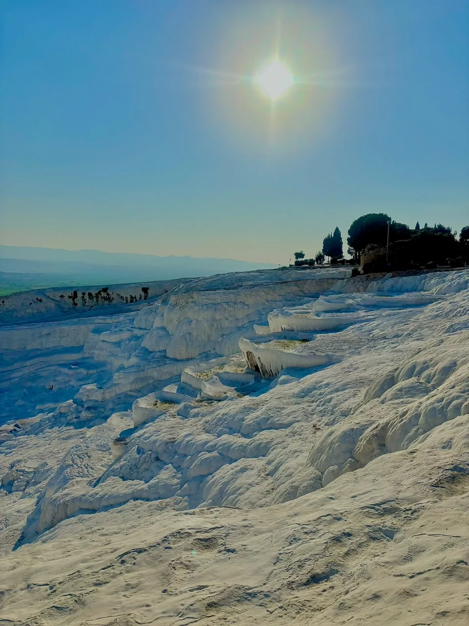 Terrazas blancas de travertino de Pamukkale bajo el sol, con el valle al fondo